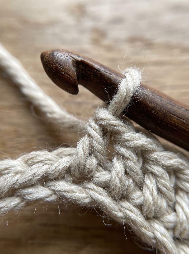 Pulling the active working loop through the first loop on the crochet hook to form the diagonal slant